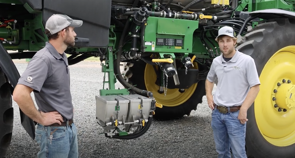 Troy Randall and Hayden Fox, 21st Century Equipment employees, standing next to a John Deere tractor with "See & Spray Ultimate" technology.